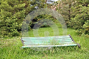 Bench in an abandoned park. The grass growing through the bench.