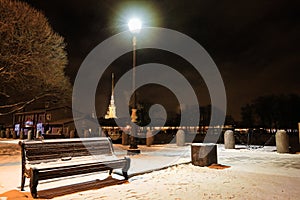 Bench, alley and street light in snowfall at night. Winter cityscape in Saint Petersburg, Russia.