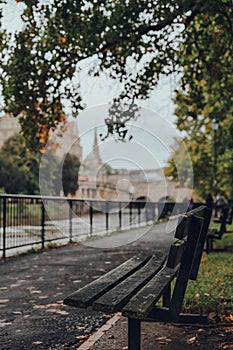 Bench on the bank of the river Avon in Bath, UK, the city on the background