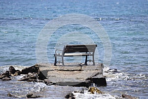 Bench on the beach. A lonely bench on the shore of the deep blue Aegean Sea.