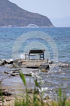 Bench on the beach. A lonely bench on the shore of the deep blue Aegean Sea.