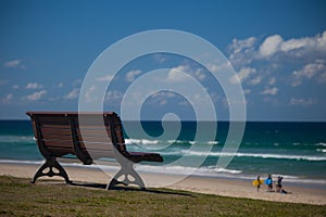 Bench by the beach with surfers in background