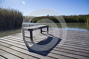 Bench casting shadow on wooden deck