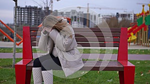 Bench on city street with desperate young pregnant woman entering sitting down holding head in hands. Portrait of sad