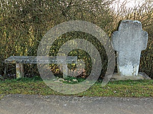 Weathered stone bench and wayside cross photo