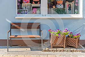 There is a bench with flowers on the street under the window