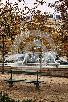 A bench and a fountain in a bright autumn park in Paris. Beautiful landscape. Vertical