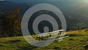 Bench green mountains nobody sit against impressive rocky landscape sunlights