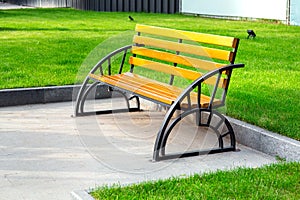 Bench with iron black legs and a brown colored wooden seat.