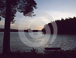 Bench by lake in beautiful sunset.