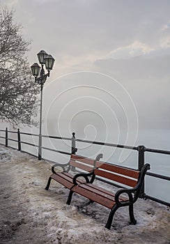 Bench and lantern on foggy winter morning