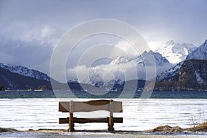 Bench looking solitary at frozen Sils lake in Engadin Switzerland with snow Alps mountains photo
