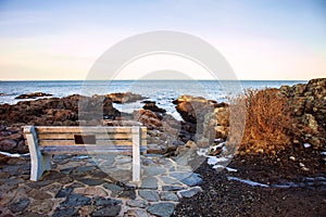 Bench on Marginal Way path along the rocky coast of Maine in Ogunquit during winter