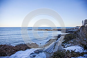 Bench n Marginal Way path along the rocky coast of Maine in Ogunquit during winter