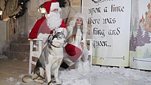 On a bench near the porch sitting Santa, the little girl and the dog Laika