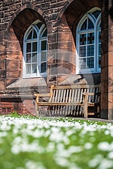 A bench nearby old red bricks building and arched windows