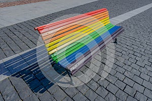 Bench painted in rainbow colors in city