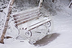 bench in the park is covered with snow