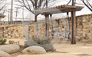 Bench pergola in park alongside stone brick wall on gravel walkway