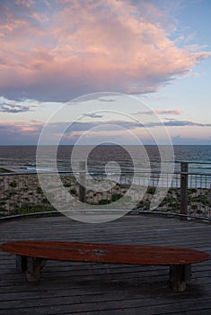 A bench in the shape of a surfboard during a sunset by the sea in Sydney