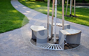 Bench sitting round with wood paneling gray metal plate three seats around a tree around a gravel threshing path in the park lawn