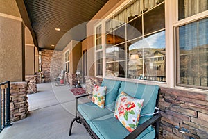 Benches against front windows at open porch of house with stone exterior wall