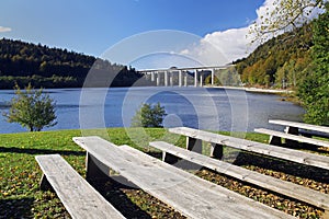 Benches on a lake with a view of highway bridge