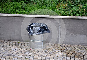 Benches by a load-bearing gray concrete retaining wall in a park. Above the wall in the flower bed. wooden park bench with metal b