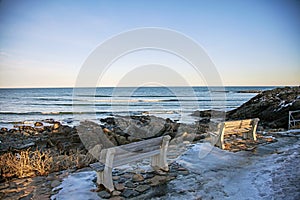 Benches on Marginal Way path along the rocky coast of Maine in Ogunquit during winter