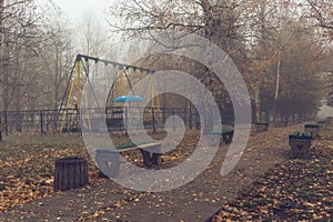 Benches in an old abandoned amusement park on a foggy autumn morning