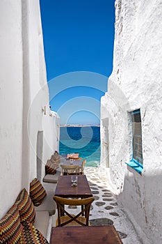 Benches and tables in a small, narrow alley in Mykonos