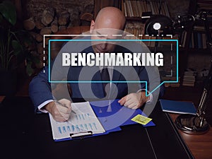 BENCHMARKING text in footnote block. Loan officer checking financial report A process of measuring the performance of a company`s