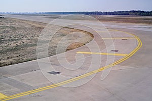 Bend in airport taxiway. Yellow markings, day, no people
