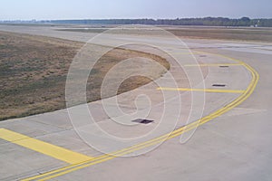 Bend in airport taxiway. Yellow markings, day, no people