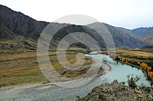 A bend of a beautiful turquoise river flowing through an autumn valley at the foot of a mountain range