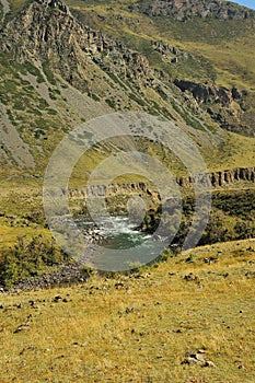 A bend in the bed of a beautiful mountain river flowing along the bottom of a deep canyon in early autumn