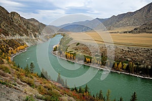 Bend the bed of a beautiful turquoise river flowing through a picturesque valley in early autumn