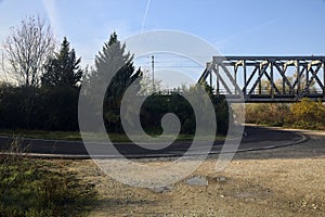 Bend in a country road under a railroad bridge