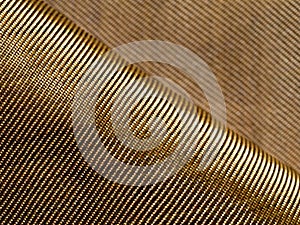 The bend of the golden fabric bulletproof material aramid. Aramid kevlar background. Golden kevlar texture and pattern