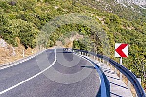 Bend road warning sign on the mountain road in summer time