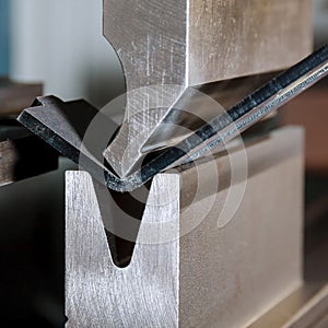 Bending sheet metal on a hydraulic machine at the factory. Bend tools, press brake punch and die. Close-up