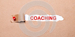 Beneath the torn strip of kraft paper attached with a red button is a white paper labeled COACHING