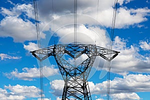 High voltage pylons against a blue sky with white clouds.