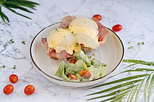 Benedict egg with bacon and salad on the white plate