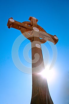 Benedictine Wooden Cross with sunflare against deep blue sky photo