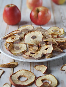 The benefits of dried fruits and vegetables. Dried apple chips and red fresh apples on a white wooden table. Organic organic food