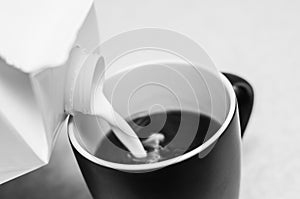 The benefits and harms of milk with coffee. Black and white photo of adding milk to coffee