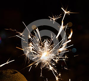 Bengal fire sparkles against the background of city lights, blurred bokeh.