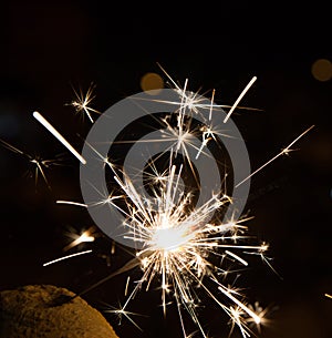 Bengal fire sparkles against the background of city lights, blurred bokeh