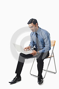 Bengali businessman using a laptop on a chair